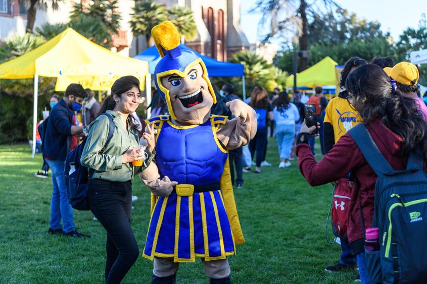 A student poses for a photo with Sammy Spartan during a campus event.