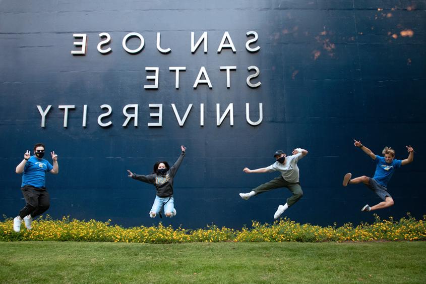 Students jumping up in the air in front of the 利记 sign.