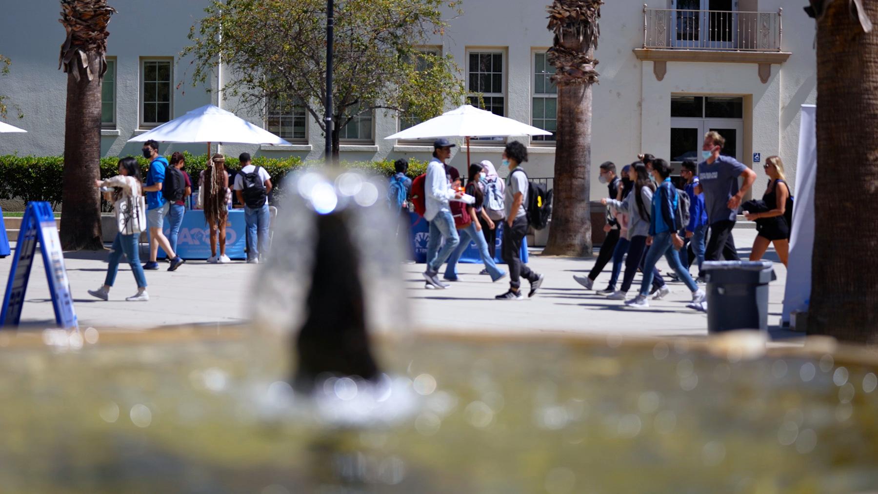 Students walking through the Paseo with a water fountain on the foreground.