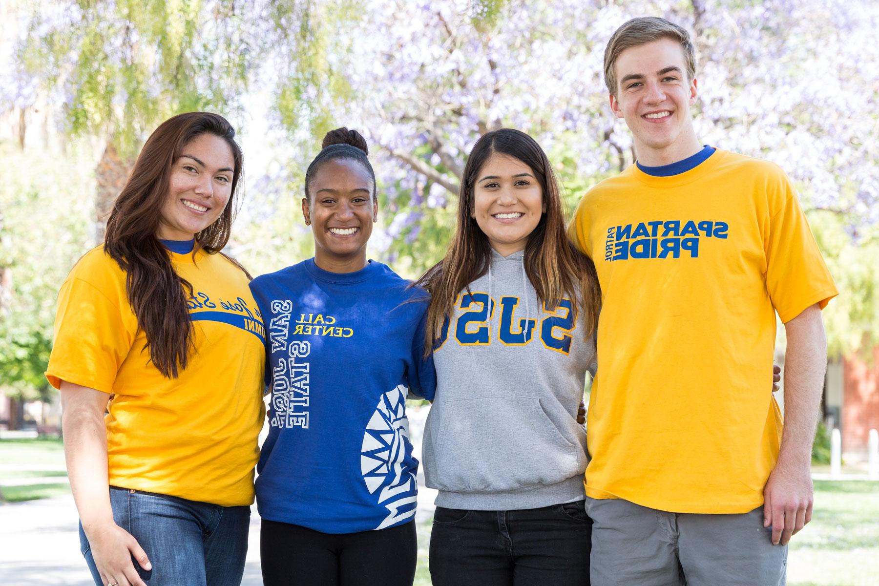 Four diverse students wearing San José State University spartan shirts smile and pose for a photo. 