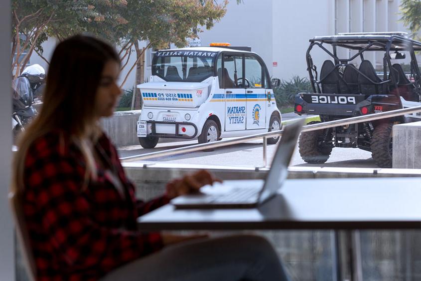 Student studying with police vehicles in the background.