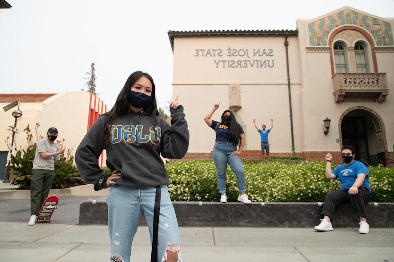 sjsu students pointing to college sign