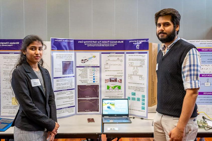 Two students standing in front of their poster.